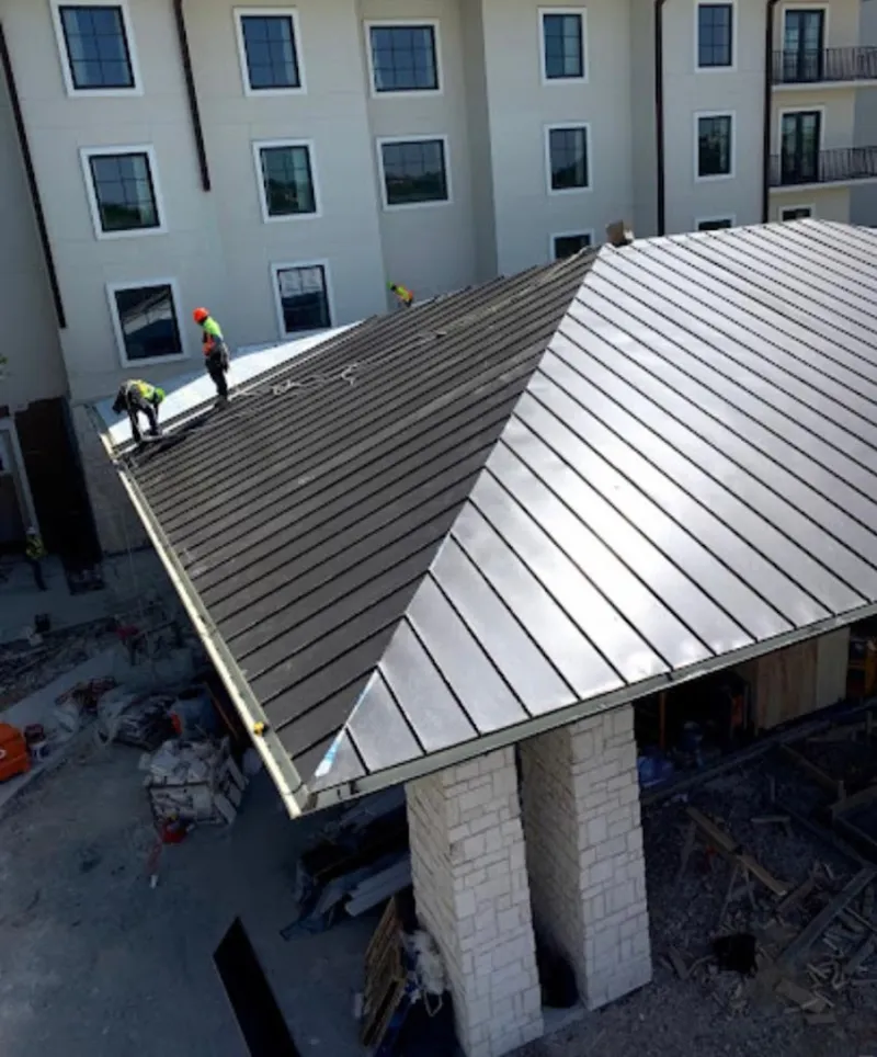 Crew installing standing seam metal roof panels on a commercial project in Bonita Springs